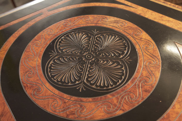 Piano lid circular motif bordered in black with a walnut circle of spiralling rope and four symmetrical anthemions carved in low relief