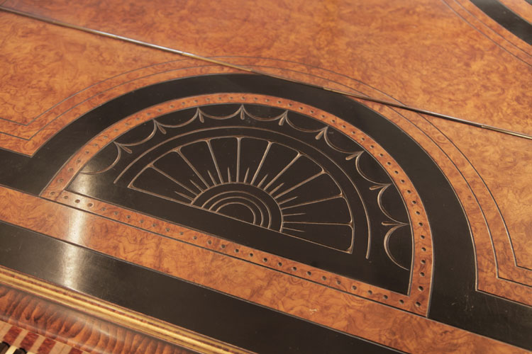 Piano lid semi-circular motif bordered in black and walnut of a sun surrounded with stylised swags and lotus leaves in low relief 