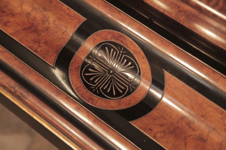 The piano fall repeats miniature versions of the decorative carvings seen on the lid. A circular motif bordered in black and walnut contains stylised palm leaves 