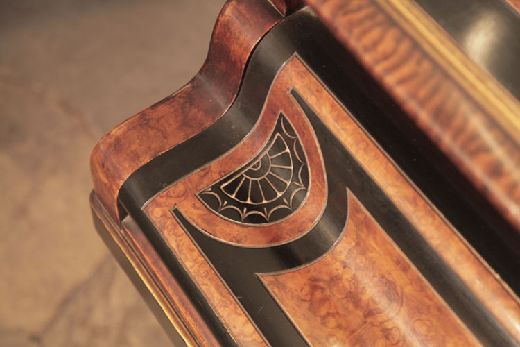 The piano fall repeats miniature versions of the decorative carvings seen on the lid. A semi-circular motif in black and walnut contains a sun motif  bordered with stylised swags and lotus leaves 
