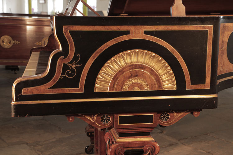 Erard serpentine piano cheek in black with burr walnut and gilt borders. Cheek features a carved motif of a sun disk surrounded by golden lotus leaves 