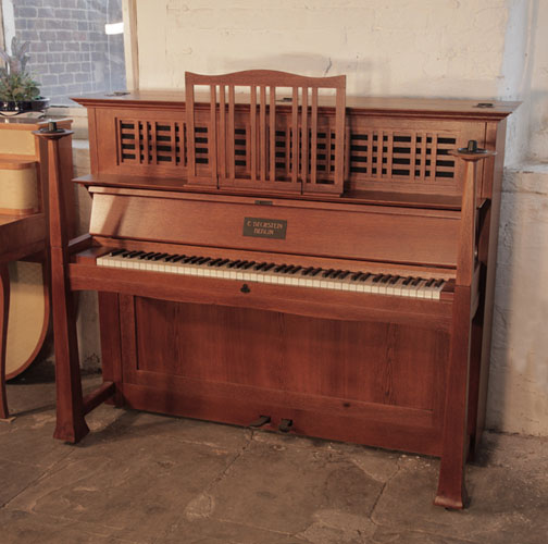 Golden Age of Pianos. Arts and Crafts, Bechstein Model 9  upright piano with an oak case. Cabinet features statement, iron hinges. Part of the cabinet design, the architectural candlesticks sit atop the square piano legs. Designed by Walter Cave. 