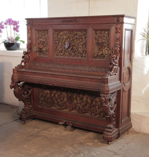 Golden Age of Pianos. Biese Hof upright piano for sale with an ornately carved, oak case and griffin legs. Cabinet features openwork panels of carved vines, musical instruments and scrolling acanthus in high relief. A true masterpiece of craftsmanship. 