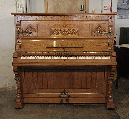 An 1895, English Gothic style, Ibach upright piano with a carved, oak case and ornate brass candlesticks and handles. Cabinet features traditional folk art motif carvings.