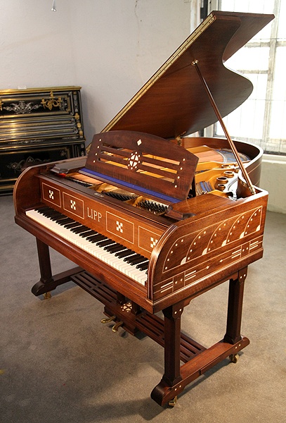 An Arts and Crafts, Lipp grand piano for sale with a mahogany case inlaid with symbols and designs from Germanic folklore. Case features ornate brass hinges and slatted cross stretcher